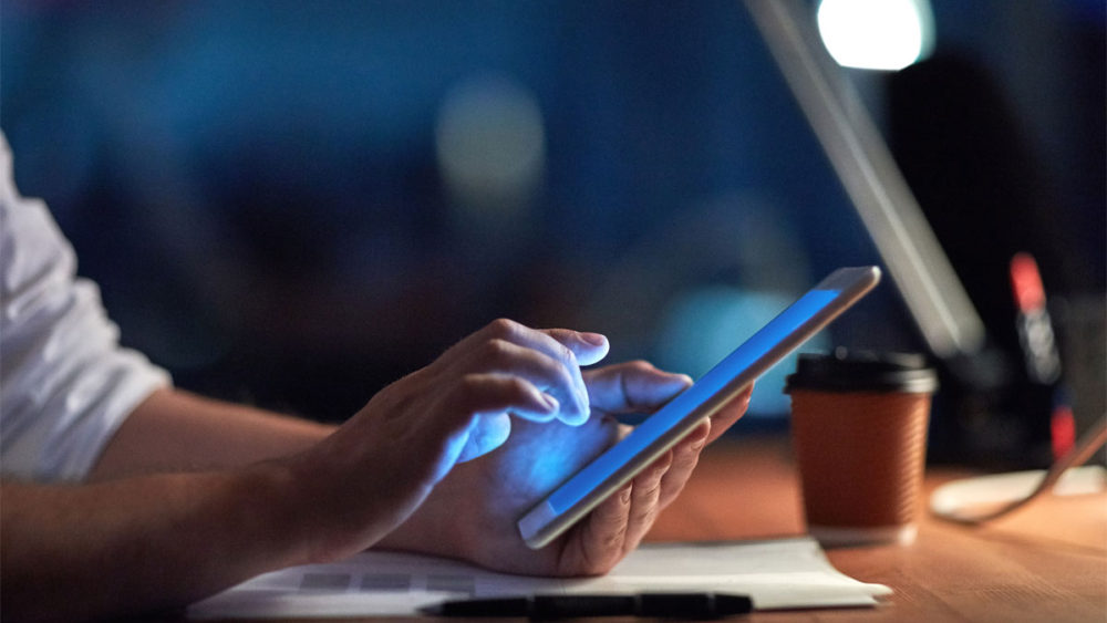 Man using an iPad and feeling the effects of electronics on his eyes