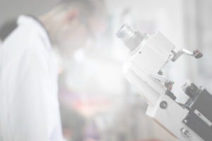 Photograph of one of Allentown Optical's lab microscopes with a lab technician in the background