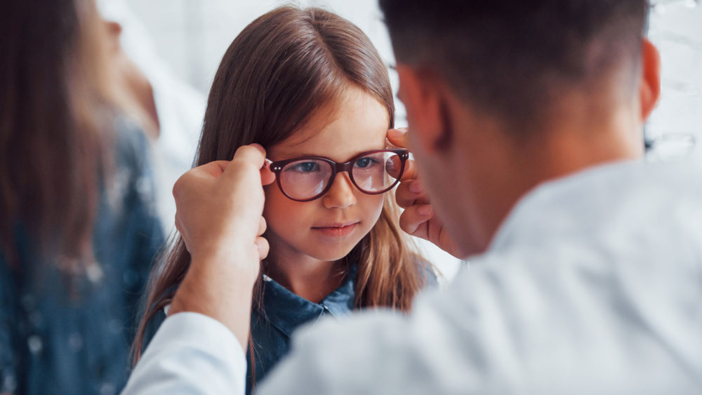 A doctor in Pennsylvania adjusts glasses for a young girl.