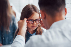 A doctor in Pennsylvania adjusts glasses for a young girl.
