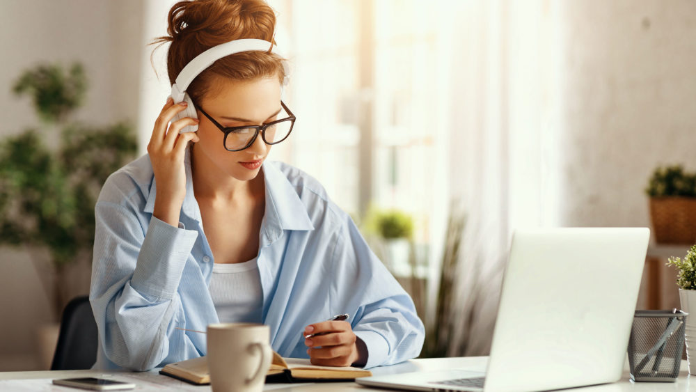 A woman in glasses working at a desk with a laptop and a cup of coffee. Optics Suppliers Pennsylvania.