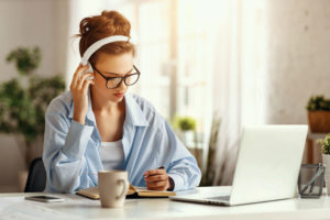 A woman in glasses working at a desk with a laptop and a cup of coffee. Optics Suppliers Pennsylvania.