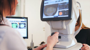 A woman getting her eyes checked at an eye exam machine. Optics Suppliers Pennsylvania. #EyeCare #Optometry #Health