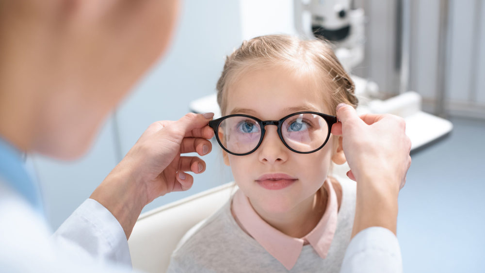 A little girl getting her glasses adjusted by an optometrist at Wholesale Optical Frames