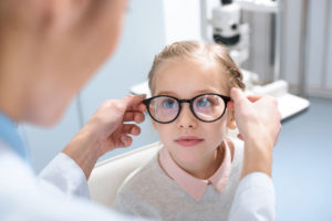 A little girl getting her glasses adjusted by an optometrist at Wholesale Optical Frames