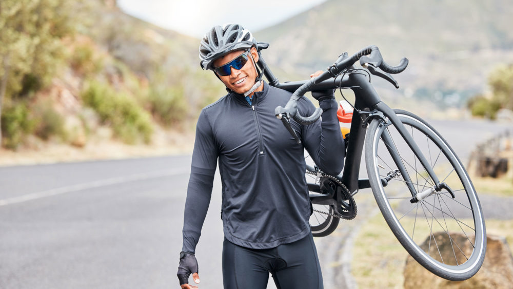 A cool dude in shades and a black shirt effortlessly carries a bike. Get your Wholesale Optical Frames here!