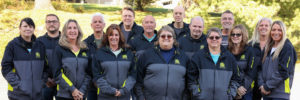 A team of people wearing black and yellow jackets, representing Optical Lens Manufacturers USA.