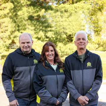 Three team members in black and grey jackets standing together. They are working optical frames in Allentown.