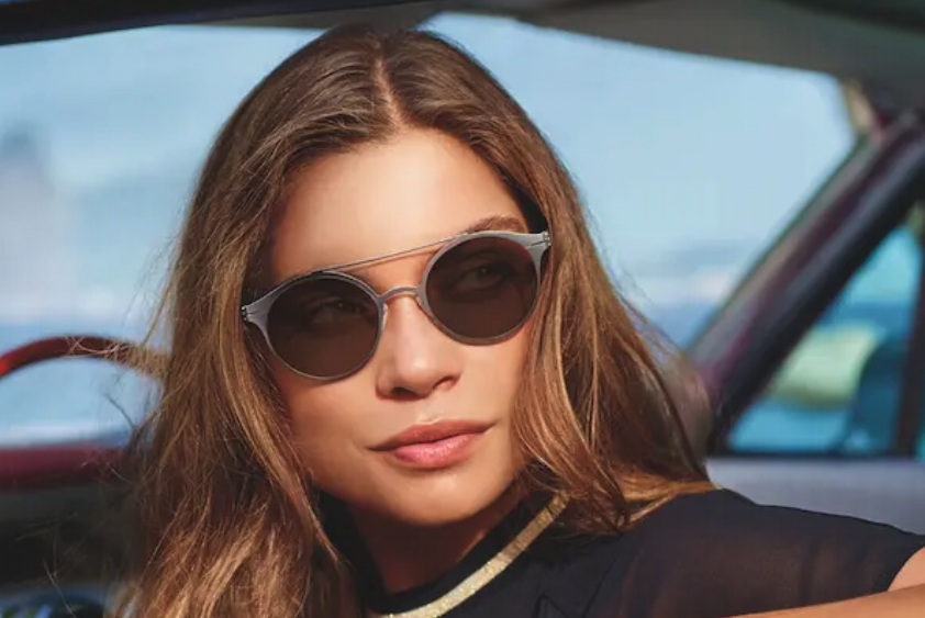 A stylish woman rocking sunglasses in a car, looking cool and ready to hit the road. #WholesaleOpticalLenses
