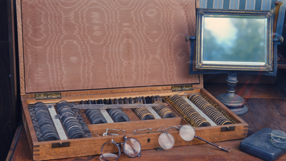 A wooden box with a mirror and glasses on a table at Wholesale Optical Labs.