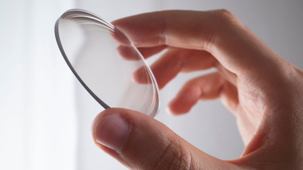 A person holding a lens in their hand at Wholesale Optical Labs.